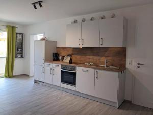 Una cocina con gabinetes blancos y un fregadero. en Fewo New Oberdorf, en Fautenbach