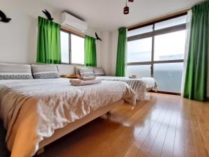 two beds in a room with green curtains at Ostay Numabukuro Hotel Apartment in Tokyo