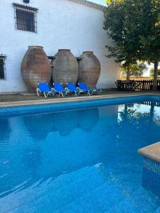 drie blauwe stoelen naast een zwembad met grote vazen bij La Huerta de Don Fernando in Villarrobledo