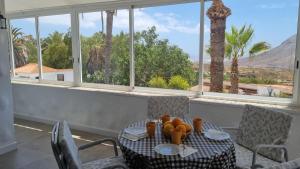 uma mesa e cadeiras com vista para uma palmeira em Villa Azure Horizon and Breeze - Panoramic Ocean View and Heated Pool em Chayofa