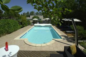 a swimming pool in a yard with a table and umbrella at Suite en Chambre d'hôtes La Vigenna in Les Ormes