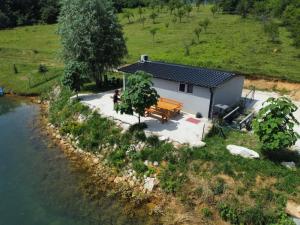 a house with a bench next to a river at Vikendica Jana Rama-Rumboci in Prozor