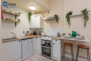 a kitchen with white cabinets and stools in it at Cosy 1 bed flat near city centre in Edinburgh