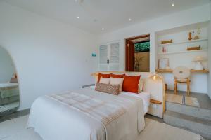 een witte slaapkamer met een groot bed met oranje kussens bij Villa Yang - New Mediterranean 5 Bed, Chef, Daily B'Fast in Dalung