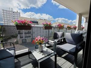 einen Balkon mit 2 Stühlen, einem Tisch und Blumen in der Unterkunft Appartement 4 pièces - La Rose des Yvelines - Classé 3 étoiles in Trappes
