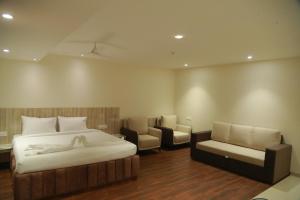 Grand Manor Suites في حيدر أباد: غرفة نوم بسرير واريكة وكرسي