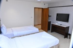 a hotel room with two beds and a television at Grand Manor Suites in Hyderabad