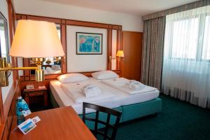 ein Hotelzimmer mit einem großen Bett und einem Tisch in der Unterkunft Hotel Amadeus Frankfurt in Frankfurt am Main