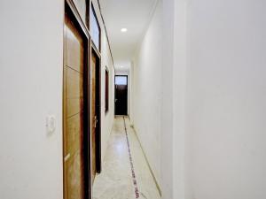 a hallway with white walls and a long hallway with paintings at Collection O The Pinaki Residency Near Dlf Avenue Saket in New Delhi
