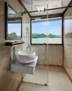 a bathroom with a sink and a glass shower at Cozy Bay Cruise in Ha Long