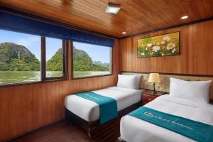 two beds in a small room with a window at Cozy Bay Cruise in Ha Long