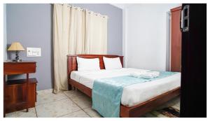 - une chambre avec un lit, une commode et une fenêtre dans l'établissement Noel Apartments, à Cochin