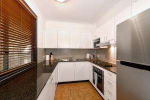 cocina con armarios blancos y nevera de acero inoxidable en Beautiful apartment in Pyrmont en Sídney