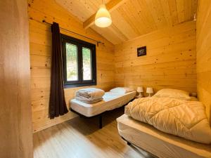 two beds in a log cabin with a window at chalet nature sur la vallée de la Truyère in Neuvéglise