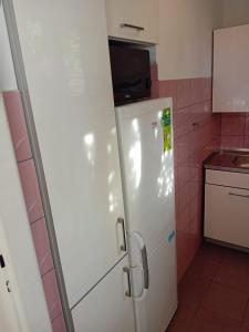 una nevera blanca en una cocina con azulejos rosas en Noclegi u Marylki, en Gniezno