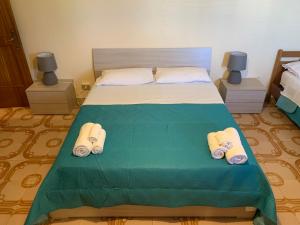 Un dormitorio con una cama verde con zapatillas. en Dimora del Sole, en Porto Cesareo