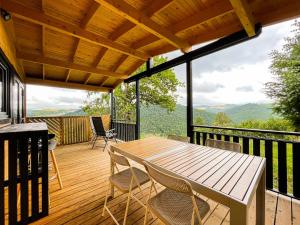 a wooden deck with a table and chairs on it at chalet nature sur la vallée de la Truyère in Neuvéglise