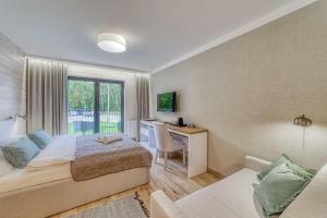 a bedroom with a bed and a desk and a window at Natura Mierzei 30 in Krynica Morska