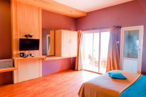 Schlafzimmer mit einem Bett und einer Glasschiebetür in der Unterkunft Hotel JK Grand in Yercaud