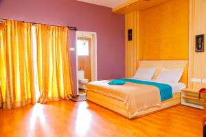 sypialnia z łóżkiem i żółtą zasłoną w obiekcie Hotel JK Grand w mieście Yercaud