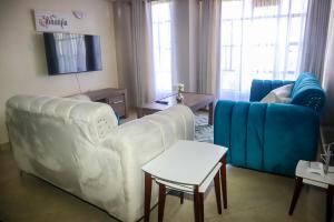 een woonkamer met een witte bank en blauwe stoelen bij Cosy Flamingo furnished apartments in Nakuru