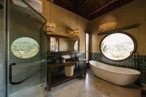 a bathroom with a tub and a large window at Lily’s Home & Retreat - Venue Travel in Tien Xuan +33 photos