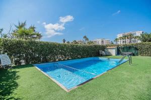 ein Pool in einem Garten neben einer Hecke in der Unterkunft Villa Pyp in Port d'Alcúdia