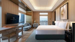 Cette chambre comprend un lit et un bureau avec une télévision. dans l'établissement Waldorf Astoria Xiamen, à Xiamen