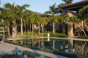 una piscina di fronte a una casa con palme di YAMA Resort a Ginosar