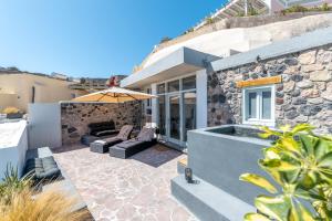 a house with a patio with an umbrella at Geminos Complex Villas in Kamari