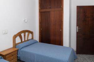 1 dormitorio con 1 cama azul y armario de madera en Trianon, 5º-29, en Cullera