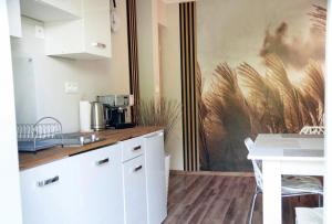 a kitchen with white cabinets and a table and a wall at Apartament Zacisze in Wieliczka