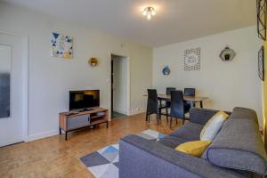 sala de estar con sofá, TV y mesa en Les Facs : Apt 6 Prs, 3 ch, Balcon et Parking, en Dijon