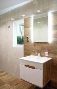 La salle de bains est pourvue d'un lavabo blanc et d'un miroir. dans l'établissement Apartament Zacisze, à Wieliczka