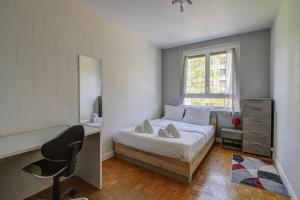 1 dormitorio con cama, escritorio y ventana en Les Facs : Apt 6 Prs, 3 ch, Balcon et Parking, en Dijon