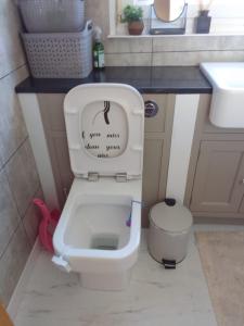 a bathroom with a toilet with a sign on it at Mide’s House in Invergowrie