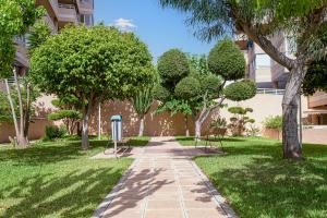 Myflats Premium Arenales Hills في آريناليس ديل سول: ممشى في حديقة فيها اشجار ومبنى