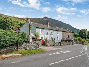 een huis aan de kant van een straat met een stenen muur bij Highside Farm in Bassenthwaite