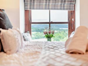 a bed with a vase of flowers in front of a window at Highside Farm in Bassenthwaite