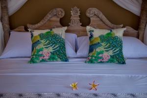 a bed with two pillows and flowers on it at Warji House 1 Ubud in Ubud