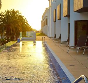 een zwembad met stoelen naast een gebouw bij ALEGRIA Barranco in Playa de las Americas