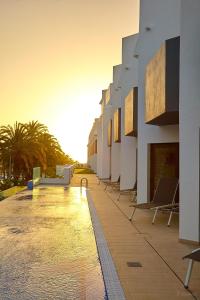 una piscina con sillas junto a un edificio en ALEGRIA Barranco, en Playa de las Américas