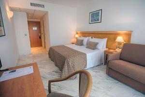 Habitación de hotel con cama y sofá en ALEGRIA Costa Ballena Aquafun en Costa Ballena