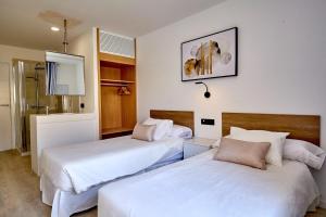 two beds in a room with white sheets at ALEGRIA Barranco in Playa de las Americas