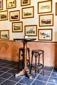 une table et deux tabourets dans une pièce avec des photos sur le mur dans l'établissement ALEGRIA Bodega Real, à El Puerto de Santa María