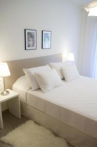 uma cama branca com almofadas brancas num quarto em SANTA SUSANNA Chic! Apartments by ALEGRIA em Santa Susanna