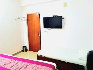a room with a bed and a television on the wall at Atlas Inn Guest House in New Delhi