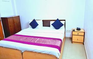 a bedroom with a bed with blue and purple pillows at Atlas Inn Guest House in New Delhi