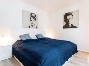 a bedroom with a blue bed with two pictures on the wall at Homefy Altstadt Apartment für 6 Personen, mit 2 Bädern und Balkon in Düsseldorf