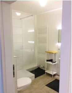 a white bathroom with a toilet and a glass shower at Homefy Altstadt Apartment für 6 Personen, mit 2 Bädern und Balkon in Düsseldorf